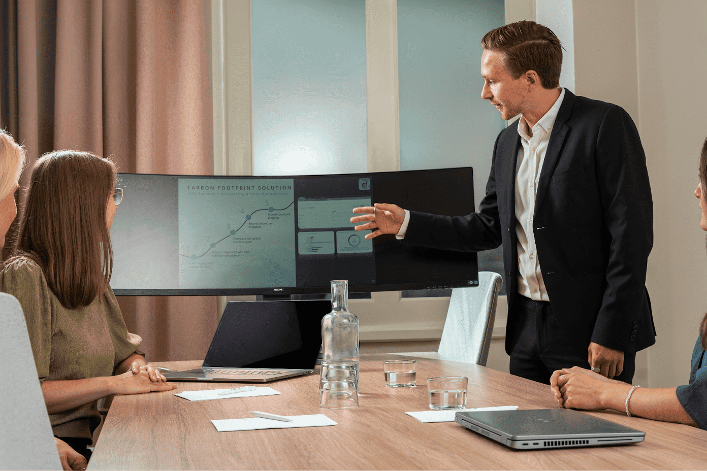 Three Cemasys employees sitting around a conference table, while another is presenting a report on a screen.