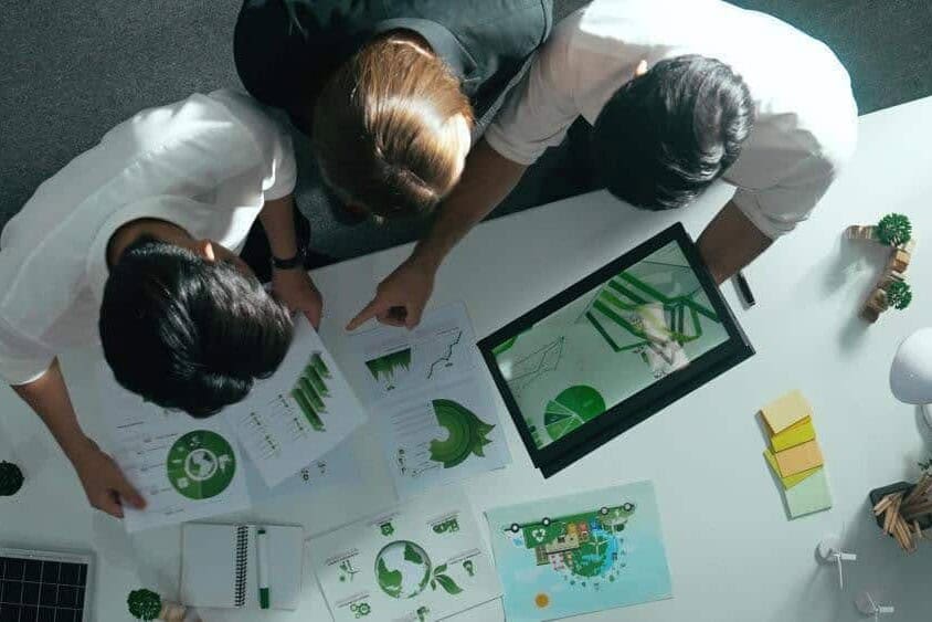 Three colleagues discussing the ESG performance of the company referencing digital and print graphs
